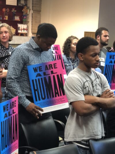 We are all human - students at school board meeting holding posters