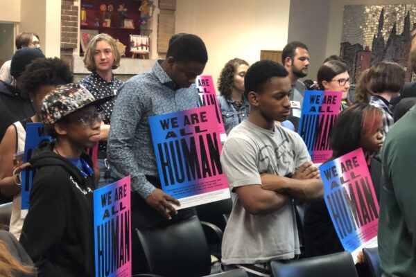 We are all human - students at school board meeting holding posters