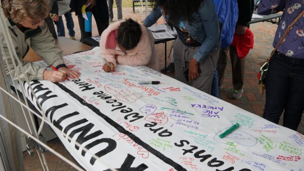 Frederick Unity Rally attendees write messages on Immigrants Welcome Here banner
