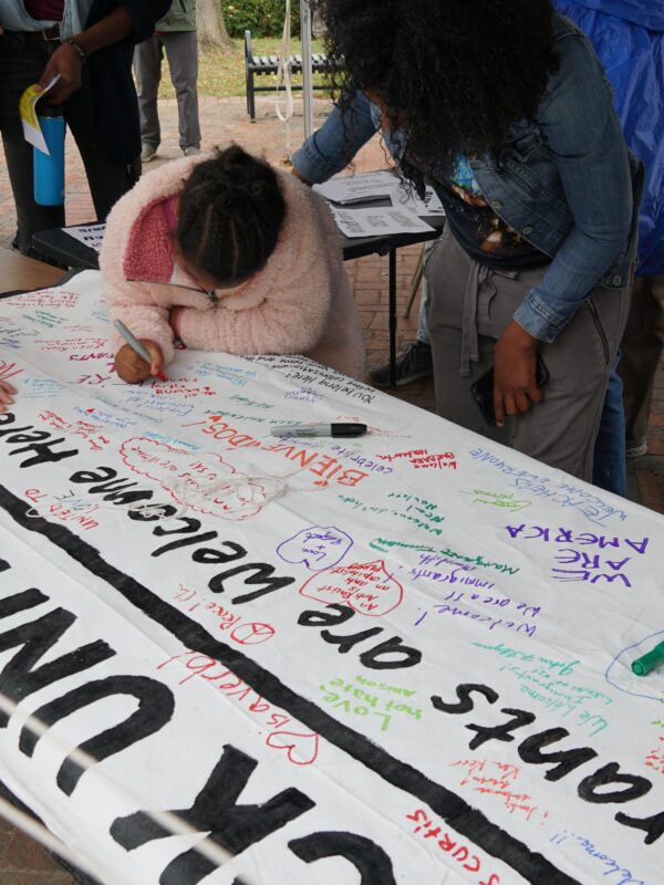 Frederick Unity Rally attendees write messages on Immigrants Welcome Here banner