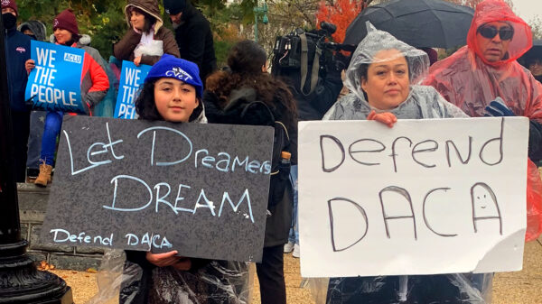 Two people at the Home is Here rally at the Supreme Court holding signs that say "Let Dreamers Dream" and "Defend DACA". In the background are two people holding ACLU signs that say "We the People".