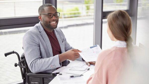 Disability Rights - Black person in a wheel chair talking to a fair-skinned person