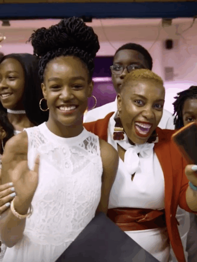 Shantay McKinily is pictured surrounded by about ten students at a formal school event. Studetns are wearing dresses and suits. Everyone is smiling.