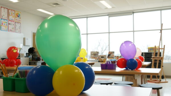 Art classroom at Bay-Brook Elementary Middle School in Baltimore, MD. There are colorful balloons on desks and lots of sunlight coming through the wall of windows.