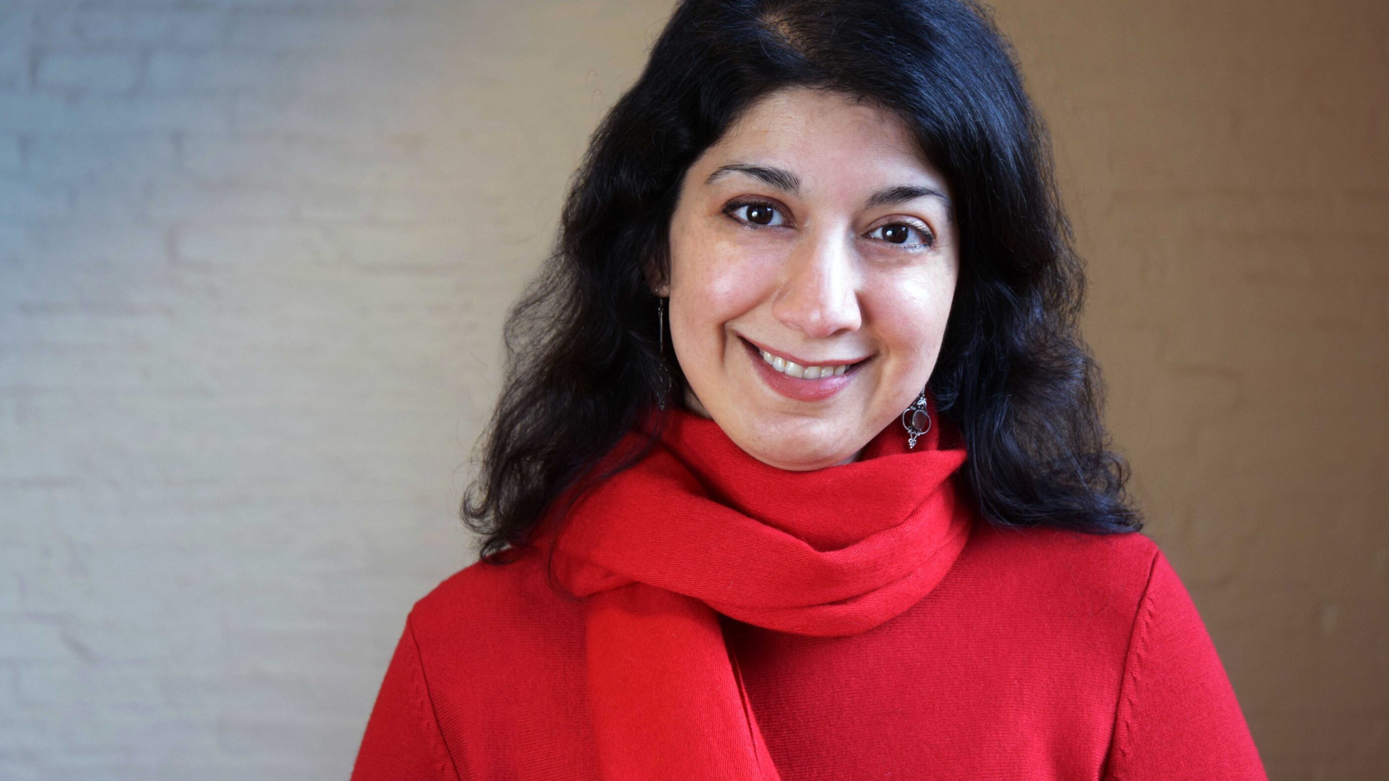 Homayra Ziad, woman with dark, medium-lenth hair, wearing a red shirt and scarf