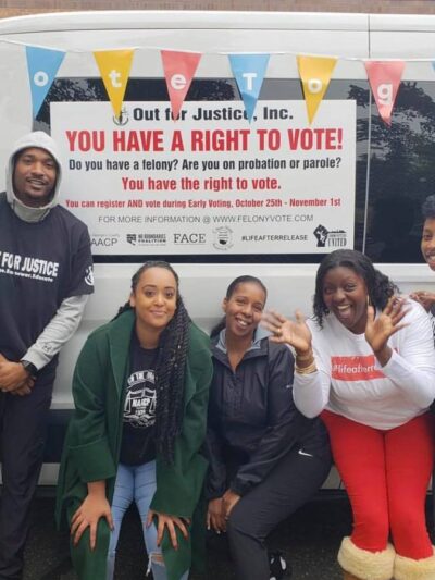 Expand the vote coalition group of people in front of a van with a sign that says, "You have a right to vote!"