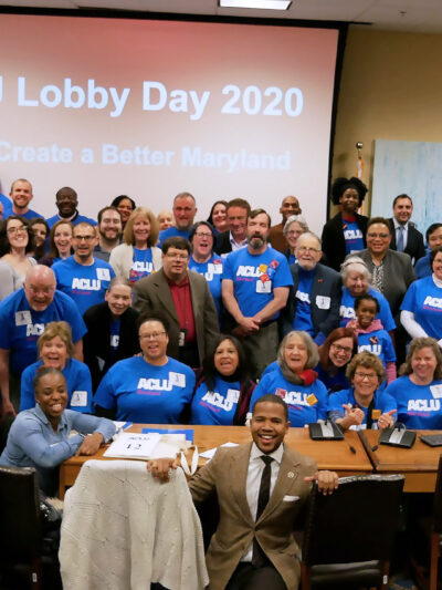 ACLU of Maryland members in a big group photo with most people wearing blue ACLU t-shirts. There are about 100 people in this photo.
