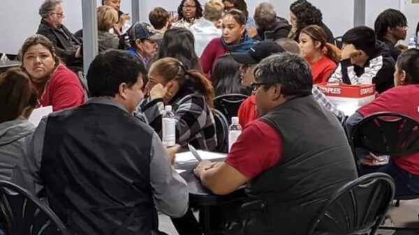 People attending a Campaign for Justice, Safety & Jobs event fill the room and are sitting around round tables.