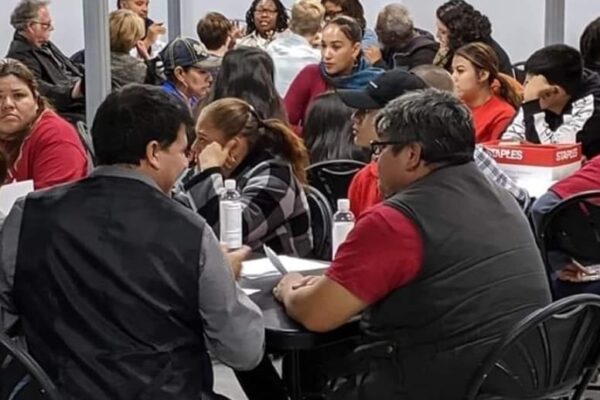People attending a Campaign for Justice, Safety & Jobs event fill the room and are sitting around round tables.