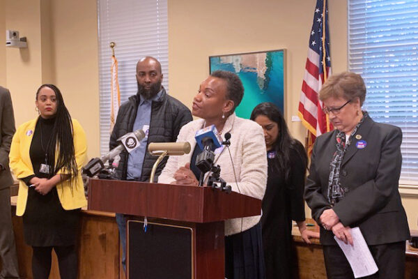 Delegate Pamela Queen spoke out against the currently unjust parole system at a parole reform press conference. She is standing at the podium with several people behind her.