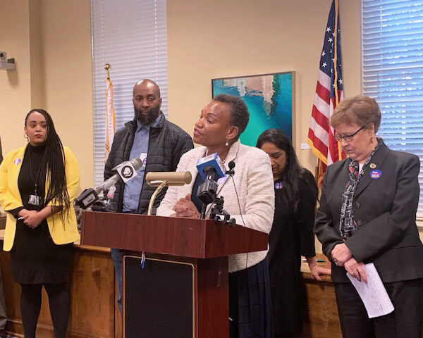 Delegate Pamela Queen spoke out against the currently unjust parole system at a parole reform press conference. She is standing at the podium with several people behind her.