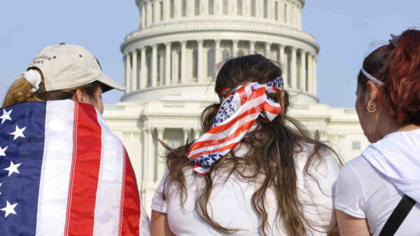 Three people are facing the US Capitol Building with American flags