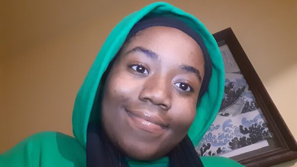 Queen Royalty is wearing a green hoodie with the hood up.