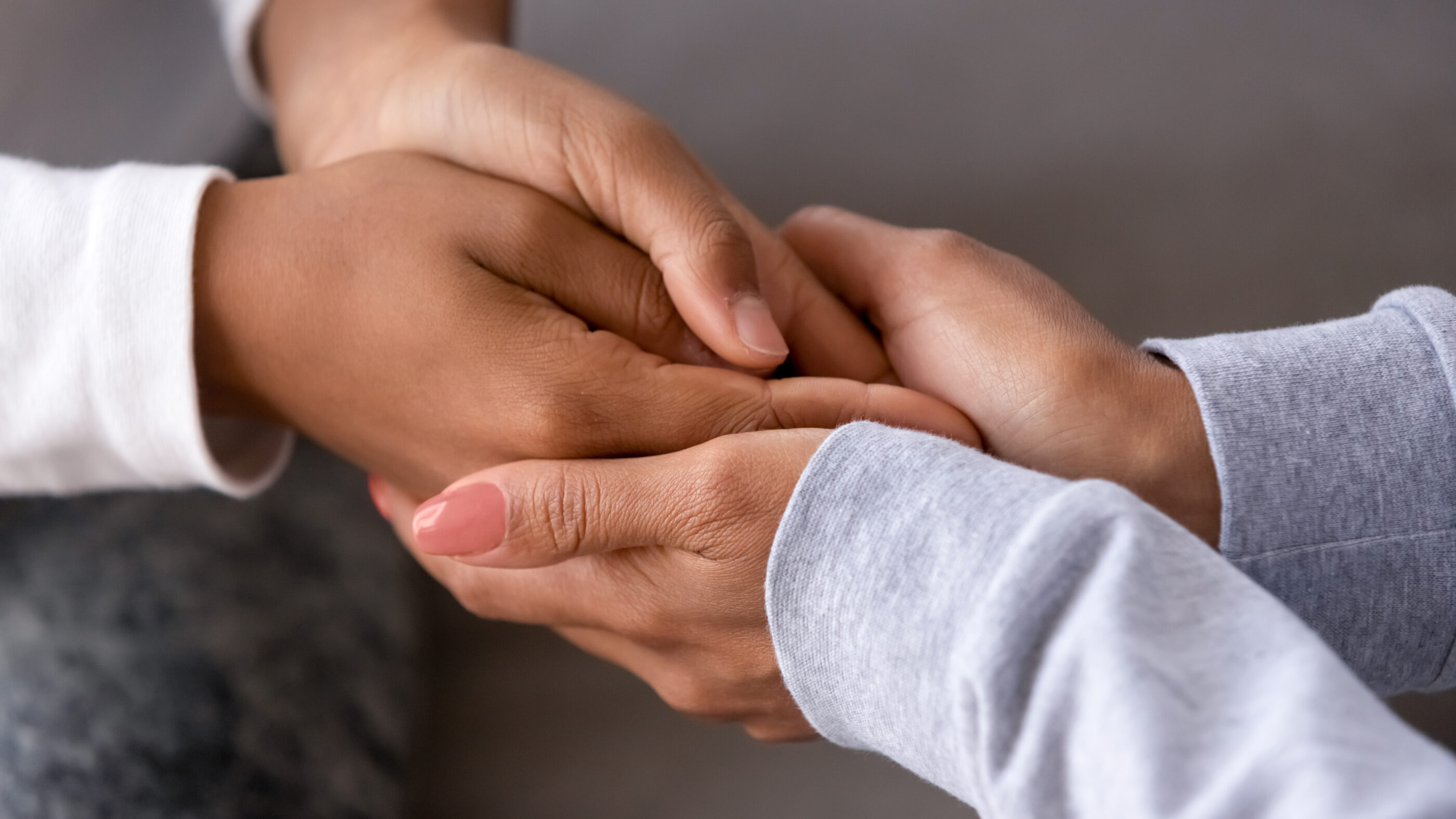 An adult is holding the hands of a child.