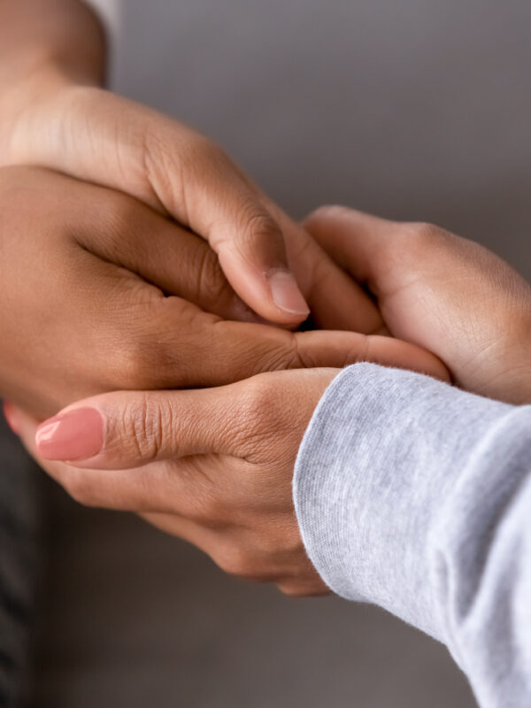 An adult is holding the hands of a child.