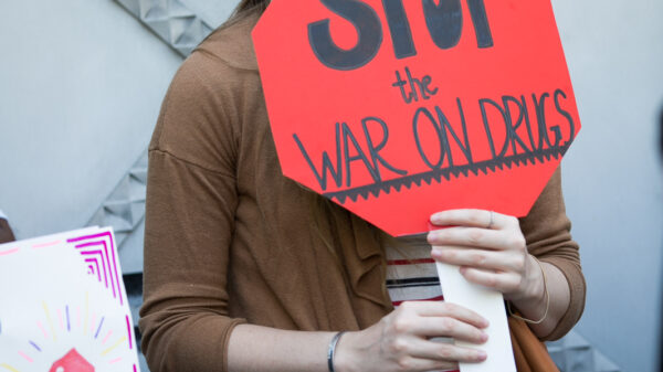 A white person is holding a sign that says