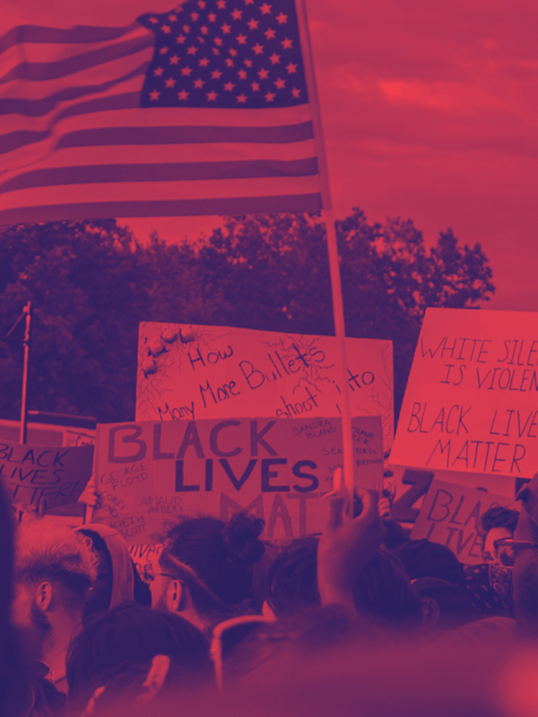 Image shows a protest for Black Lives Matter with a red and navy blue filter on it. People are holding a flag and protest signs.