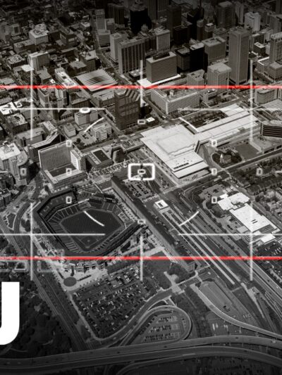 It is a black and white photo with a red target sign pointed at the city of Baltimore below. There is also a white ACLU name on the left of the picture.