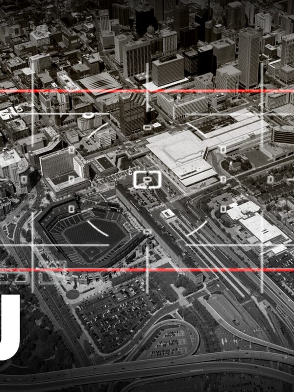 It is a black and white photo with a red target sign pointed at the city of Baltimore below. There is also a white ACLU name on the left of the picture.