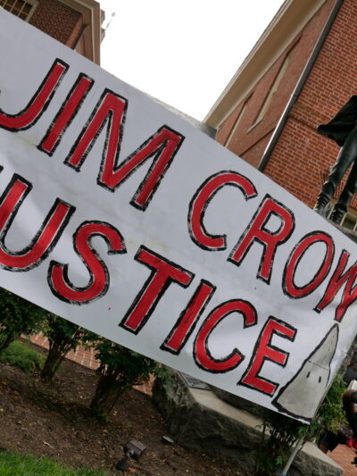 Jim Crow Justice banner is held up in front of the Talbot Boys Confederate statue on the courthouse lawn in Easton, Maryland.