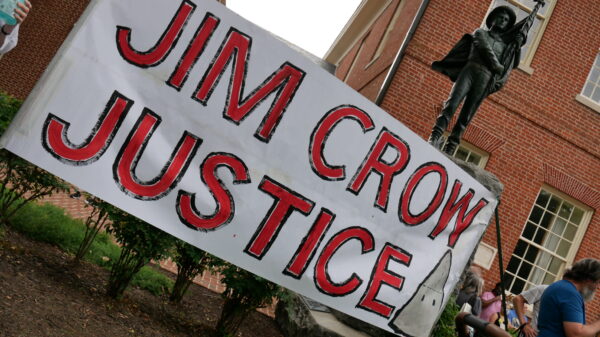 Jim Crow Justice banner is held up in front of the Talbot Boys Confederate statue on the courthouse lawn in Easton, Maryland.
