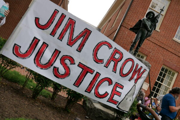 Jim Crow Justice banner is held up in front of the Talbot Boys Confederate statue on the courthouse lawn in Easton, Maryland.