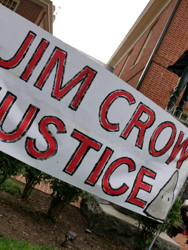 Jim Crow Justice banner is held up in front of the Talbot Boys Confederate statue on the courthouse lawn in Easton, Maryland.