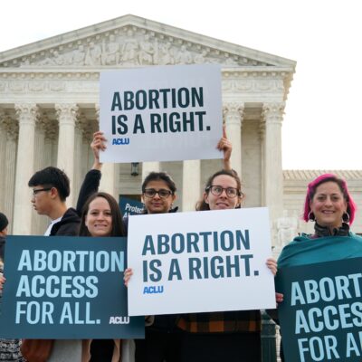 Protesters hold ACLU abortion rights posters in front of the Supreme Court.