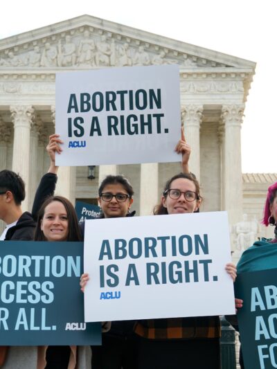 Protesters hold ACLU abortion rights posters in front of the Supreme Court.