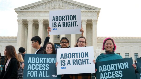 Protesters hold ACLU abortion rights posters in front of the Supreme Court.