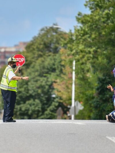 A crossing guard is guiding two students across a street.