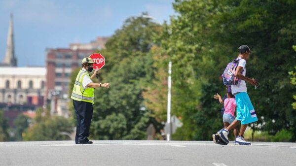 A crossing guard is guiding two students across a street.
