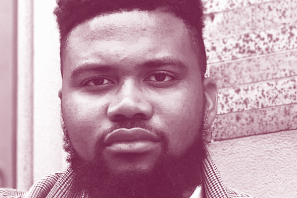 Nehemiah Bester is a Black man with short hair and a beard, and is wearing a sport jacket, collared shirt, and tie. Image has a burgundy and white gradient map color profile.