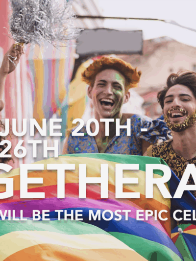 Group of people of various light to dark skin tones is laughing together holding a rainbow flag.