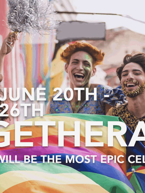 Group of people of various light to dark skin tones is laughing together holding a rainbow flag.