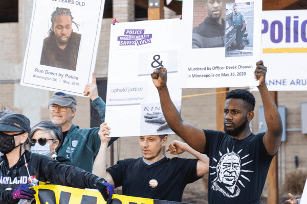 Protesters at a police accountability rall holding up signs with photos of Black people killed by police.