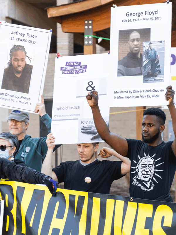 Protesters at a police accountability rall holding up signs with photos of Black people killed by police.