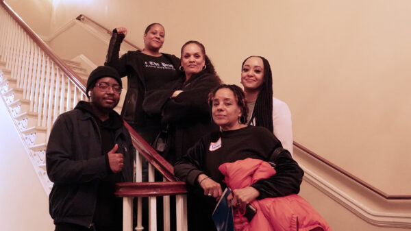 Black activists standing on stairs at the ACLU of Maryland Lobby Day event. One person has their fist raised. Activists are lobbying their legislators at the event for civil rights.