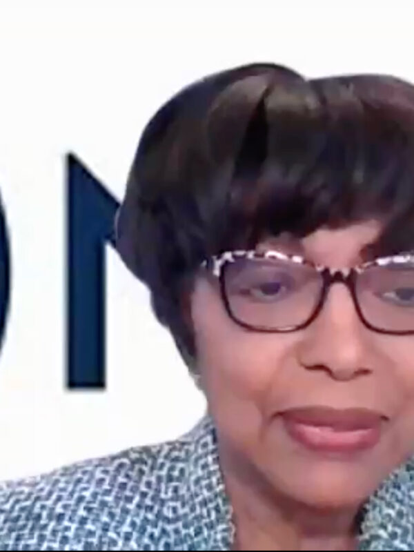 Dr. Willie Woods is a Black woman with medium brown skin. She has short dark hair, is wearing glasses, and is in front of a virtual background with part of the NAACP logo visible behind her.