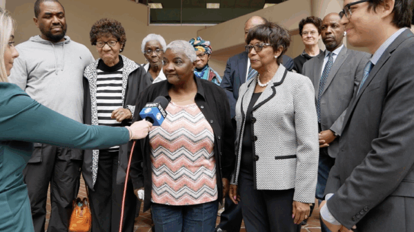 Group of plaintiffs and advocates from Federalsburg, Maryland, and lawyers from the ACLU of Maryland stand outside of a court buidling. A reporter is holding a microphone up to plaintiff Roberta Butler.