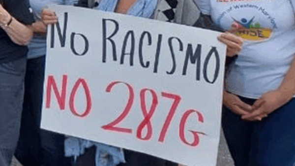 People hands shown holding a protest sign that says, "No Racismo, no 287g."