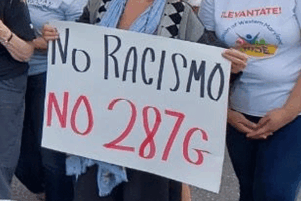 People hands shown holding a protest sign that says, "No Racismo, no 287g."