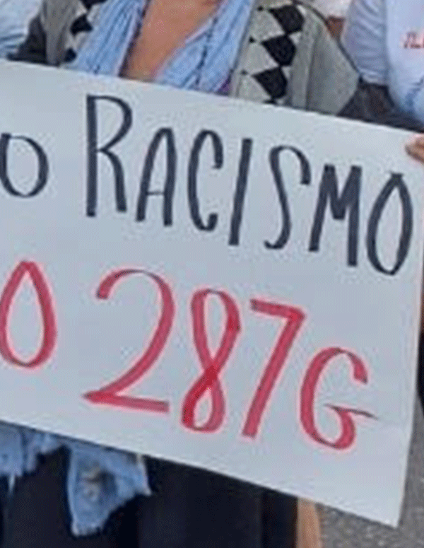 People hands shown holding a protest sign that says, "No Racismo, no 287g."