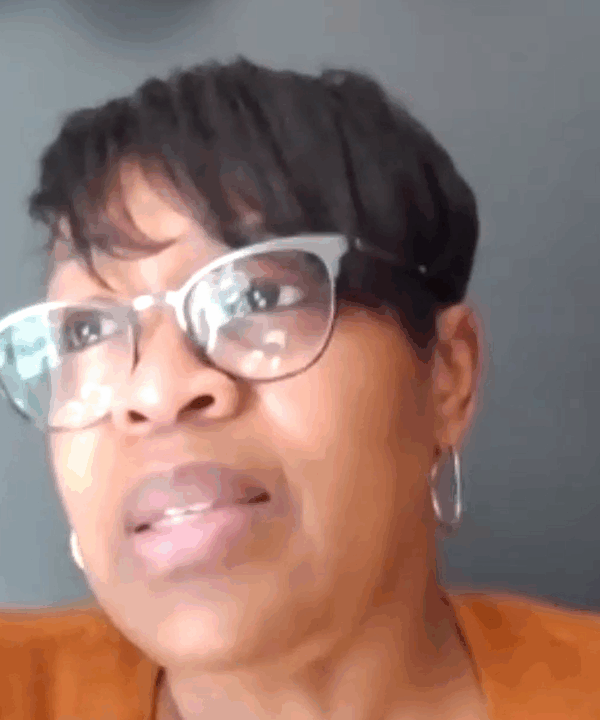 Josette Blocker is a Black woman with short hair swooped to the side. She is wearing cat-eye glasses and is looking toward the upper left of the screen.