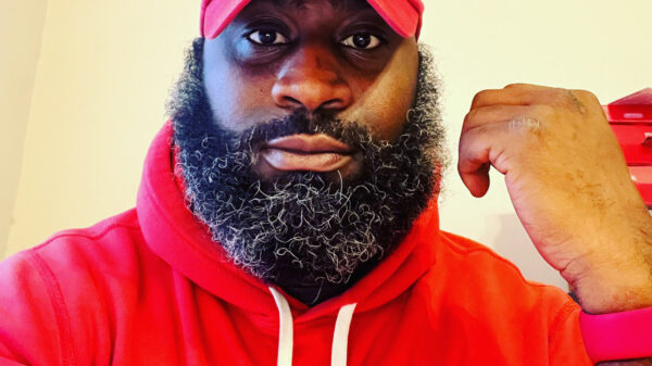 Ron Williams is a Black man wearing a red hat and hoodie, has a beard, and is looking at the camera. The text says, "End Police Stops and Searches Based on the Smell of Marijuana."
