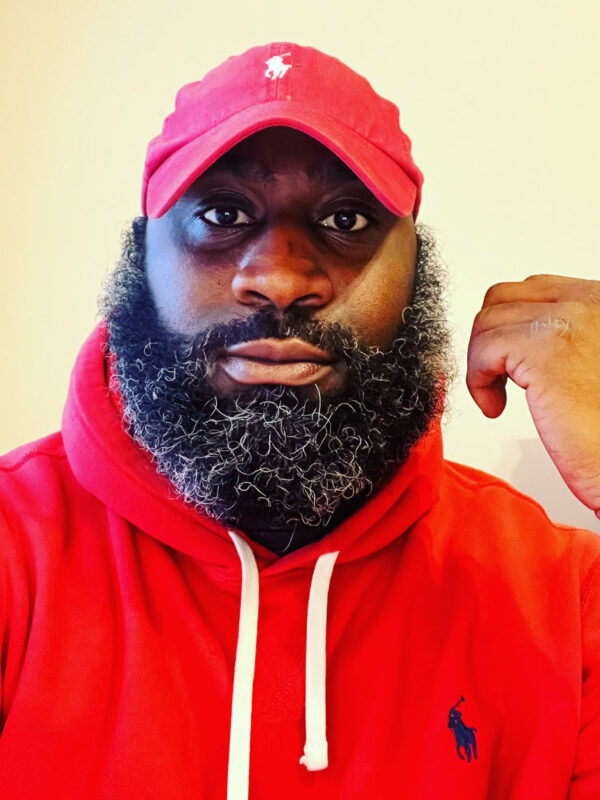 Ron Williams is a Black man wearing a red hat and hoodie, has a beard, and is looking at the camera. The text says, "End Police Stops and Searches Based on the Smell of Marijuana."
