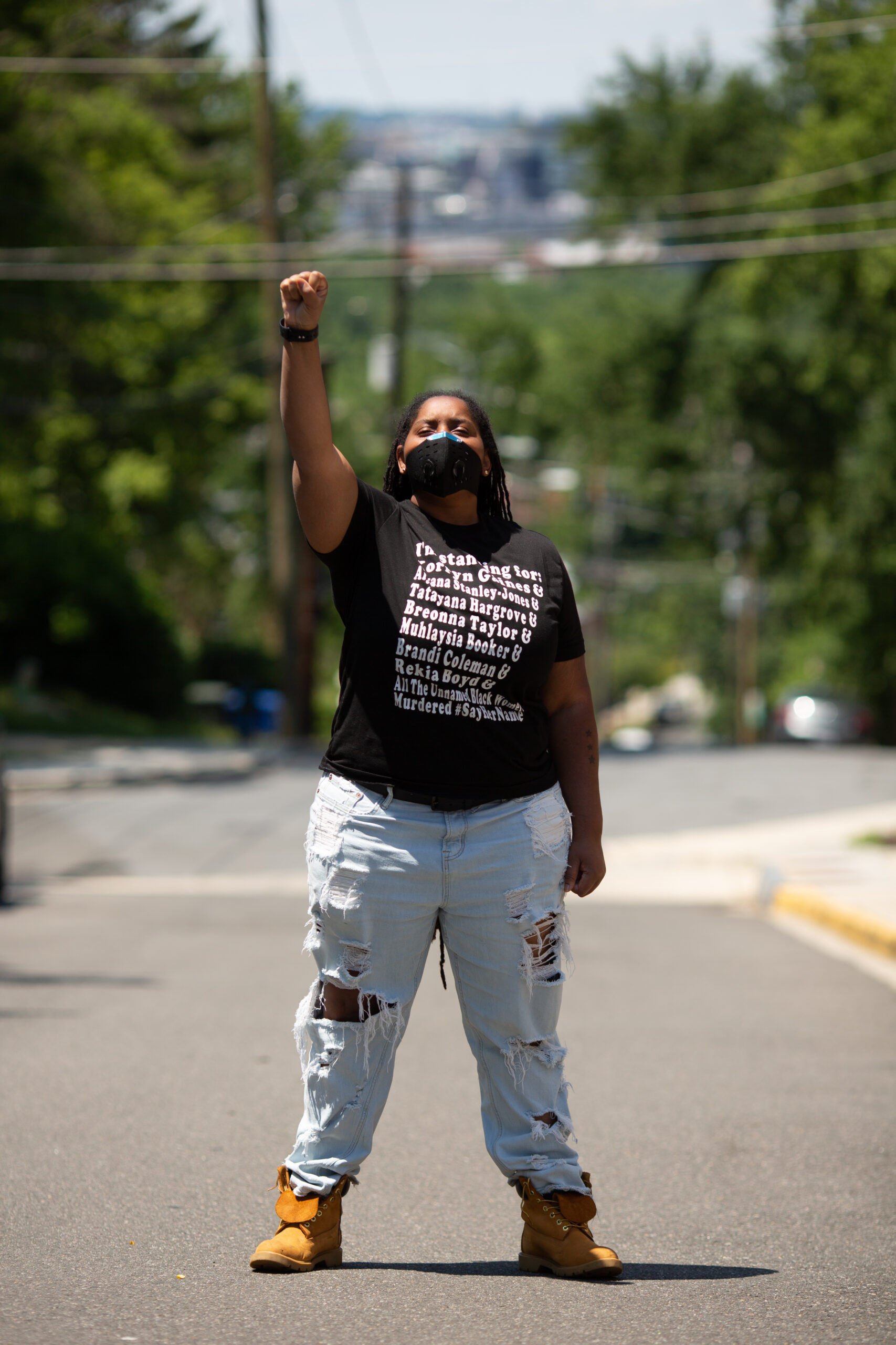 Black person with fist in the air wearing a t-shirt with the names of Black people killed by police