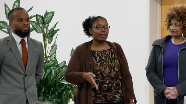 Brandy James is a Black woman who was recently elected to serve in the Federalsburg government. She is wearing glasses and has her hair. There is a Black man wearing a gray suit on her left and a Black woman with natural curly hair on her right.