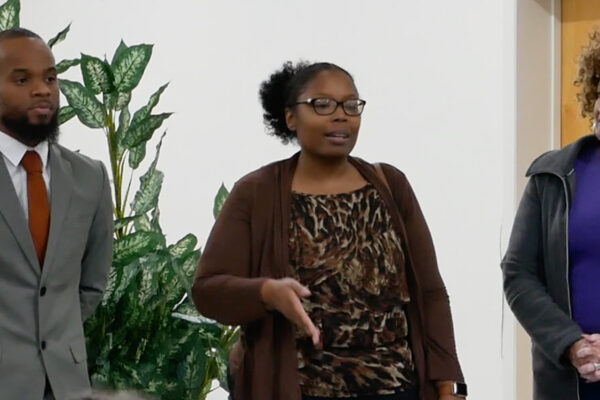 Brandy James is a Black woman who was recently elected to serve in the Federalsburg government. She is wearing glasses and has her hair. There is a Black man wearing a gray suit on her left and a Black woman with natural curly hair on her right.