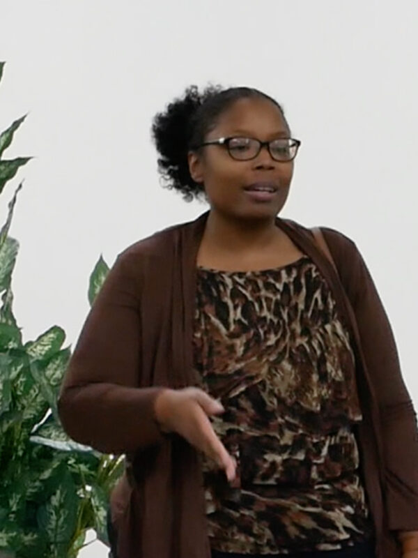 Brandy James is a Black woman who was recently elected to serve in the Federalsburg government. She is wearing glasses and has her hair. There is a Black man wearing a gray suit on her left and a Black woman with natural curly hair on her right.